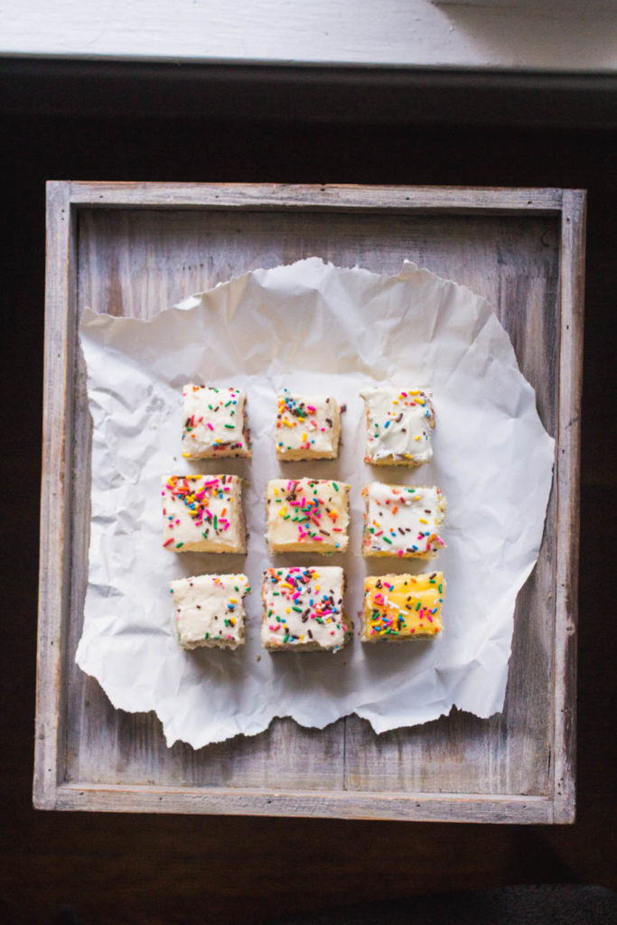 9 slices of different sprinkle cake recipes on white parchment paper.