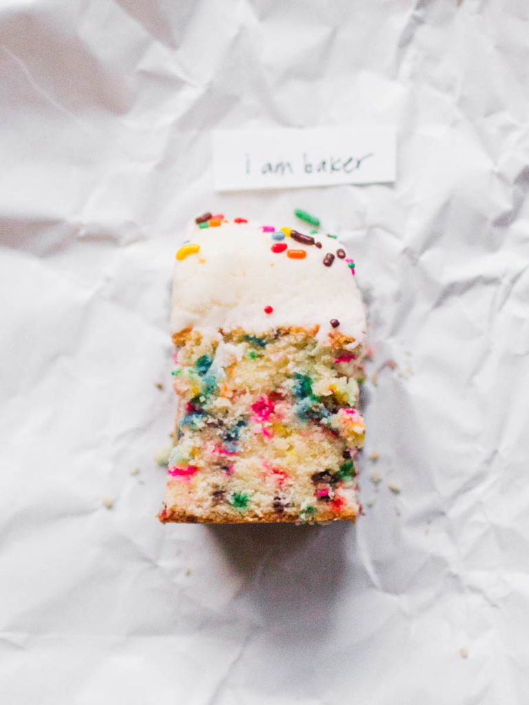 Single slice of I am Baker sprinkle cake recipe one white parchment paper.