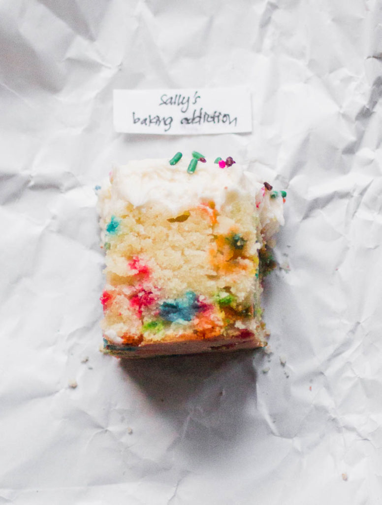 Single slice of Sally\'s Baking Addiction sprinkle cake on white parchment.