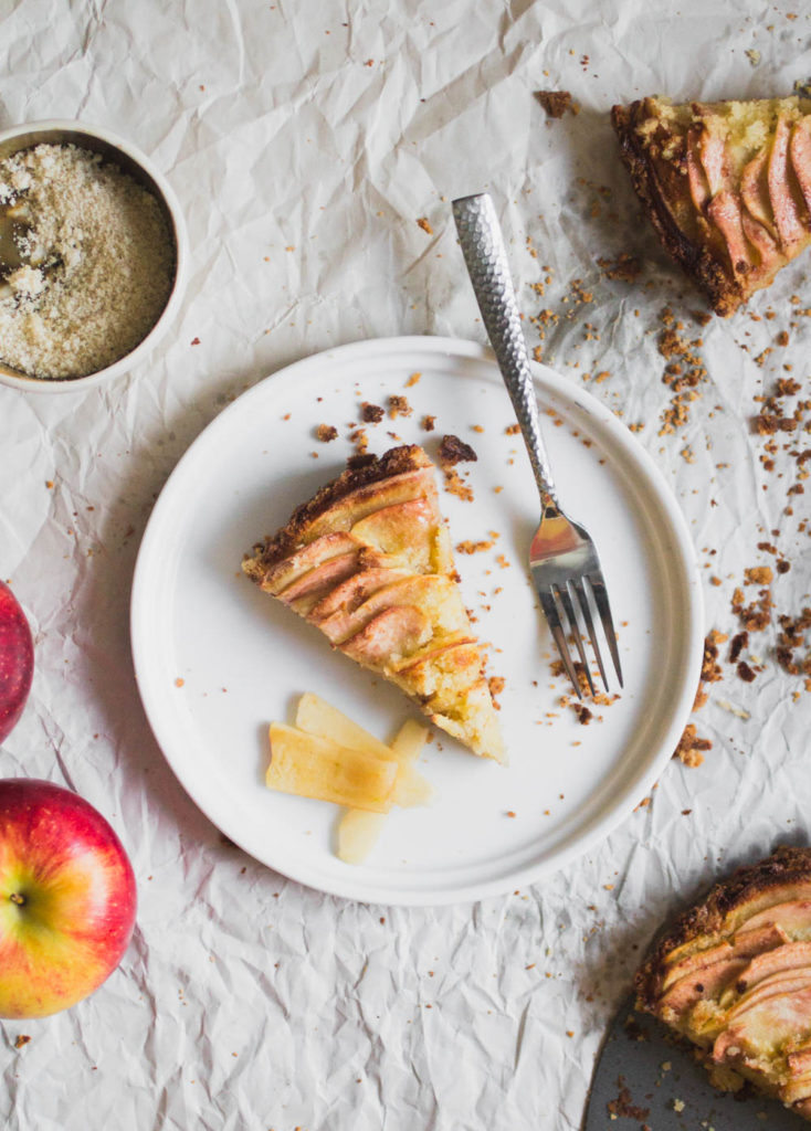A slice of apple tart on a white plate with a fork.