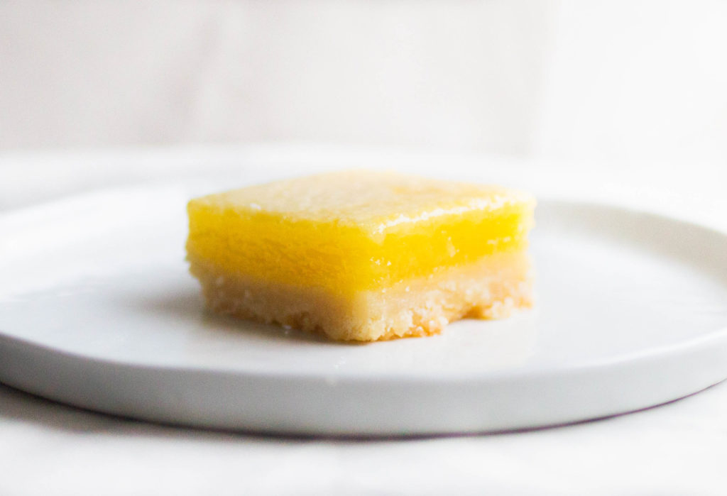 single slice of sally\'s baking addiction lemon bars on white plate.