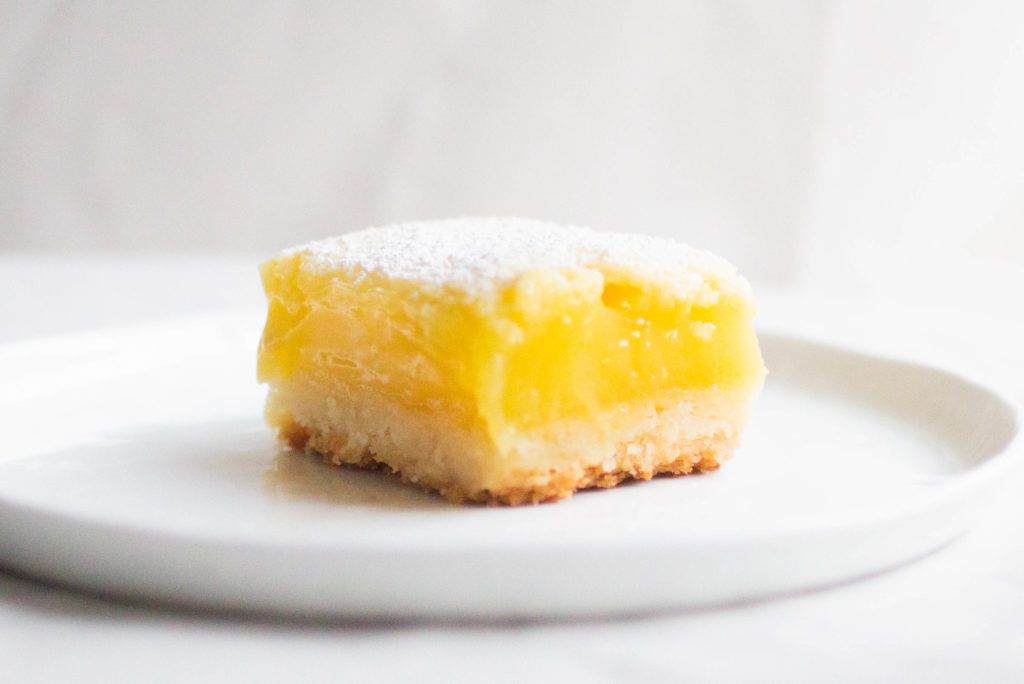 single slice of ina garten\'s fluffy golden lemon bar recipe on white plate.