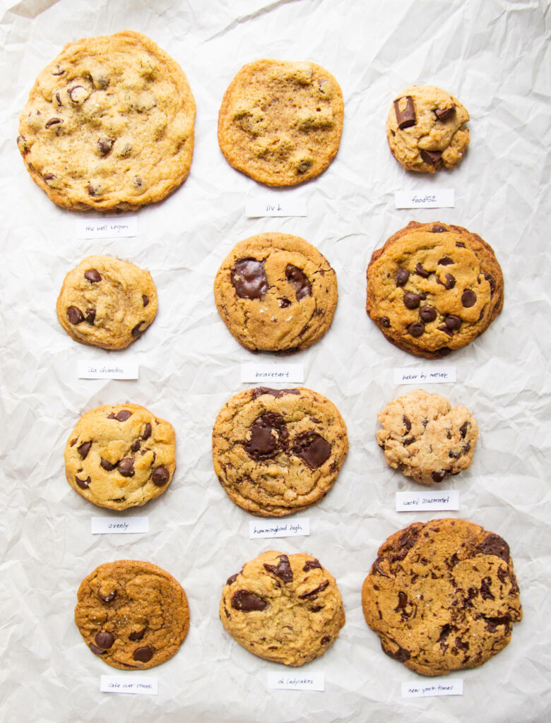 12 different vegan chocolate chip cookie recipes lined up on parchment paper.