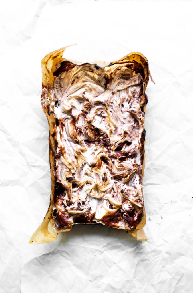 Overhead view of a meringue swirled with chocolate on top of a rectangular cake.