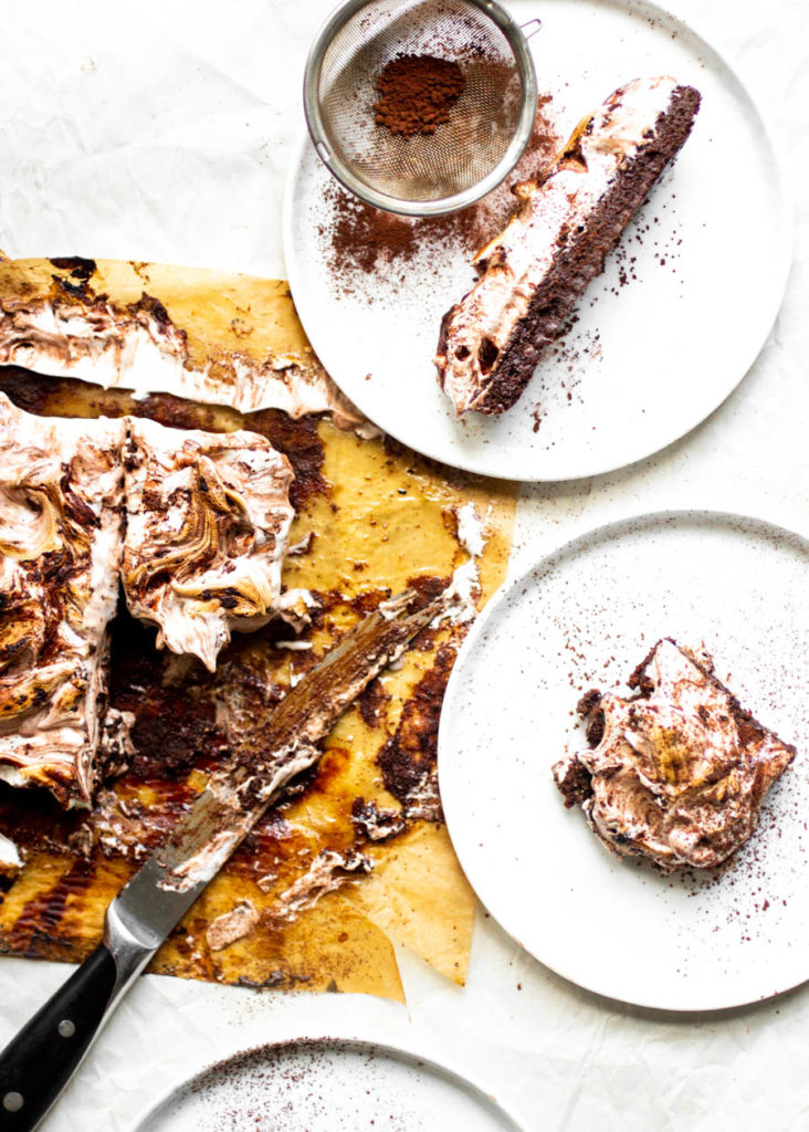 Slices of chocolate cake with toasted meringue on white plates.