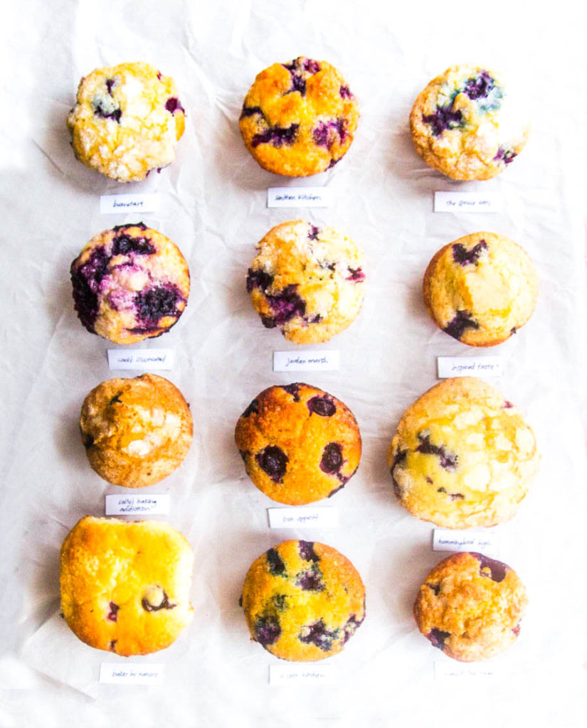 overhead view of 12 lined up blueberry muffins on white parchment paper.
