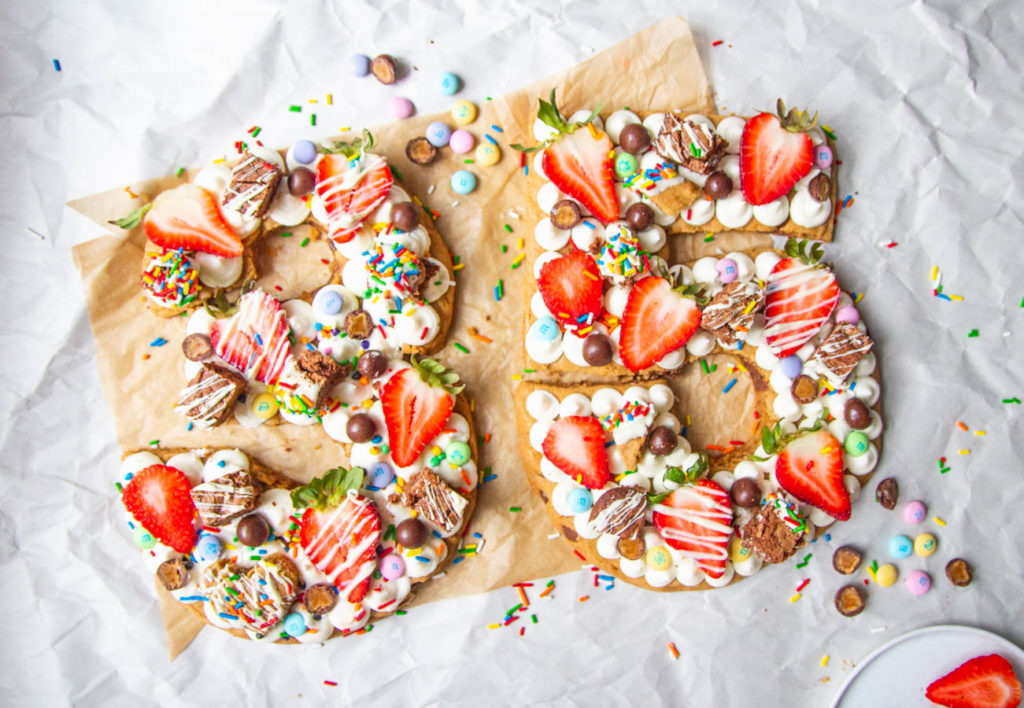 birthday cookie cake shaped like the numbers 35 topped with frosting, fruit and candy.