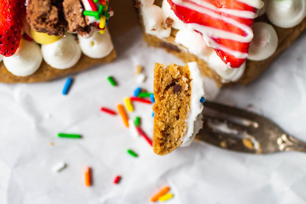 slice of birthday cookie cake with frosting and strawberry.