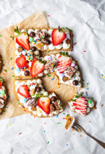 birthday cookie cake shaped like the numbers 35 topped with frosting, fruit and candy.