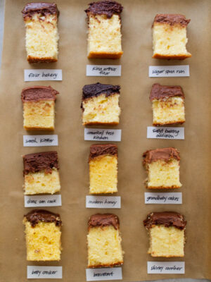 9 different slices of yellow cake with chocolate frosting on a brown background.
