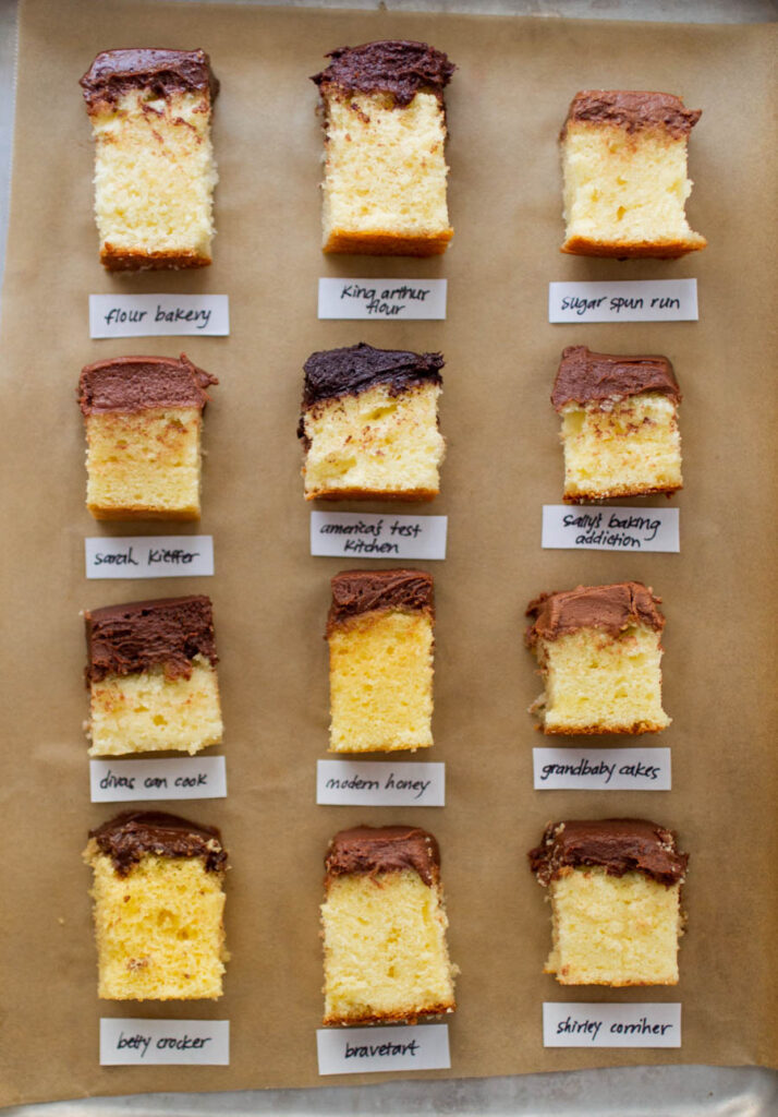 9 different slices of yellow cake with chocolate frosting on a brown background.