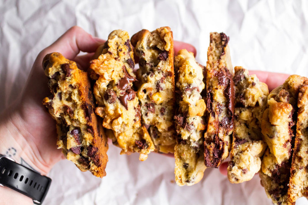 Two hands holding 6 halves of different Levain copycat cookies.