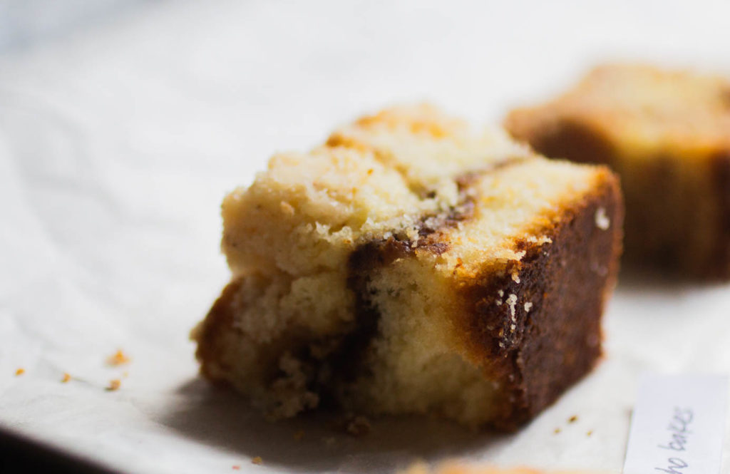 Close up of a square of coffee cake on a white background.
