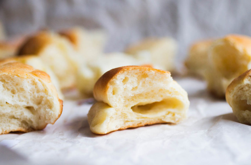 Close up of half of a Parker House Roll on a white background.