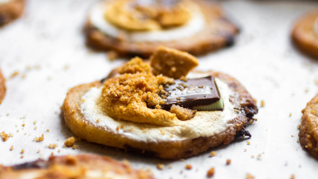 Close up on the graham crunch and Andes mint sticking out of a s\'mores cookie.