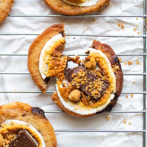 A smore's cookie broken in half on a wire baking rack.