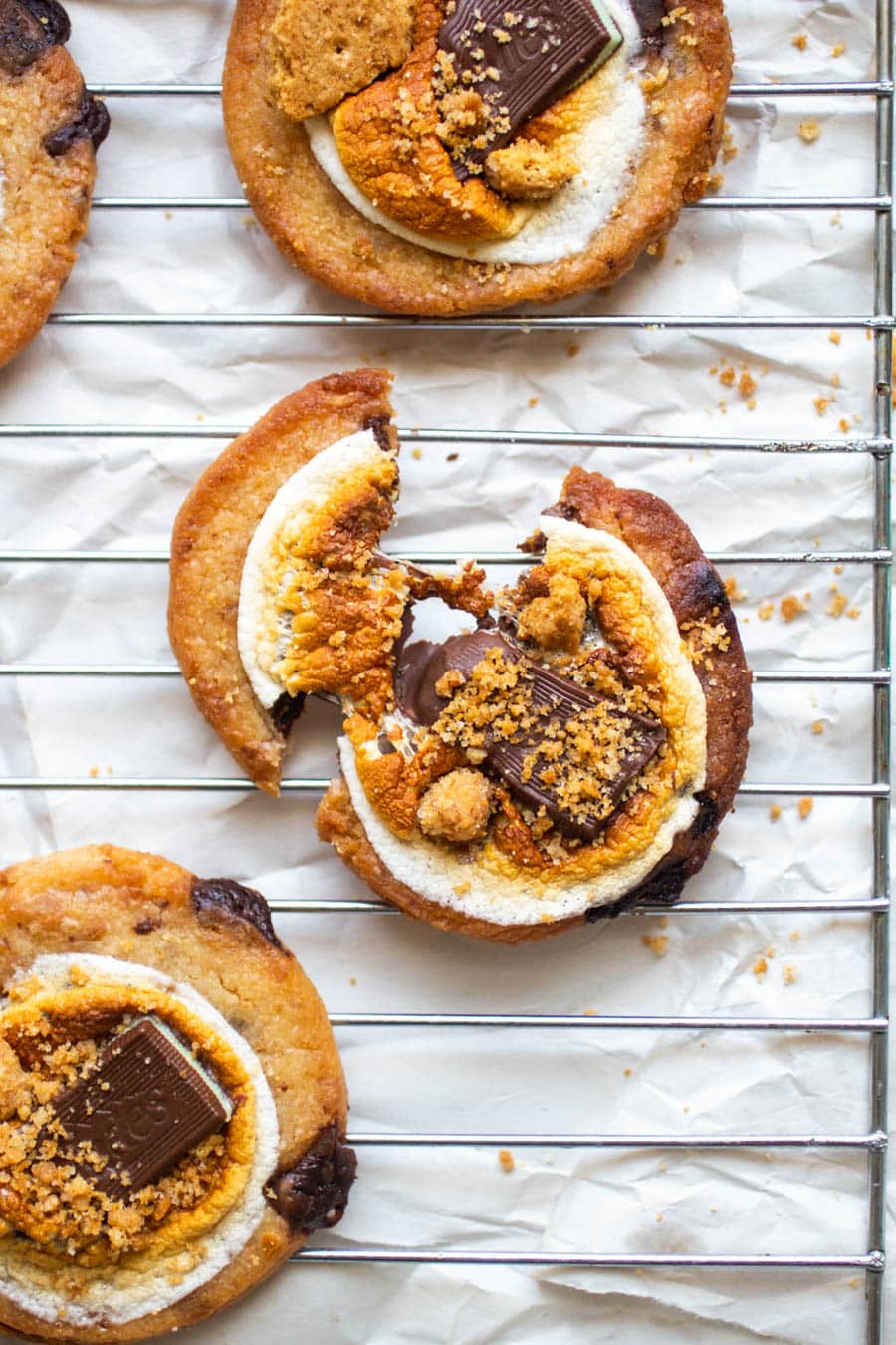 A smore\'s cookie broken in half on a wire baking rack.