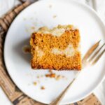 A slice of gingerbread coffee cake on a white plate with a fork.