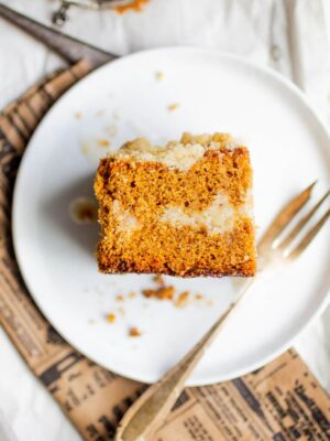 A slice of gingerbread coffee cake on a white plate with a fork.