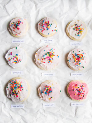 9 frosted sugar cookies with sprinkles on a white background.