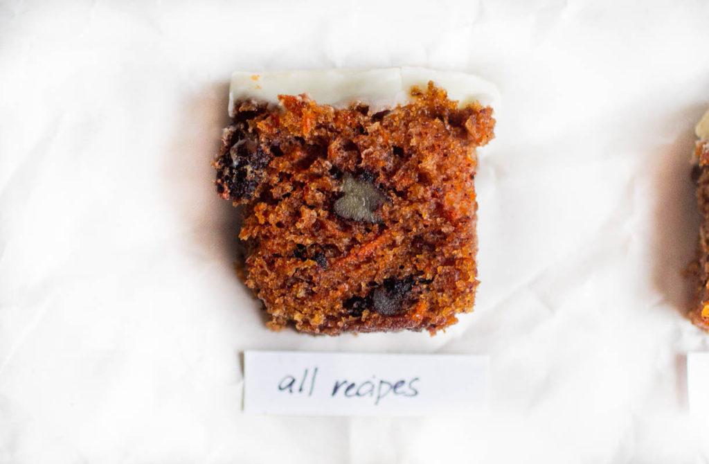 Single slice of all recipes carrot cake recipe on white parchment paper.