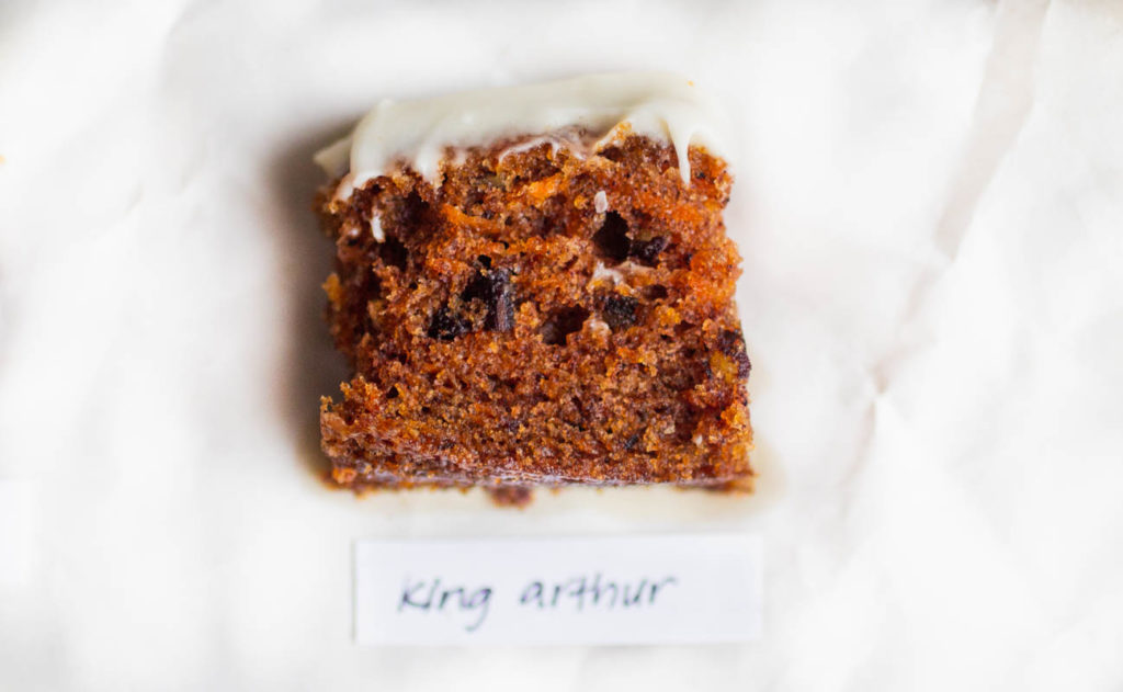 Slice of king arthur carrot cake recipe on parchment paper.