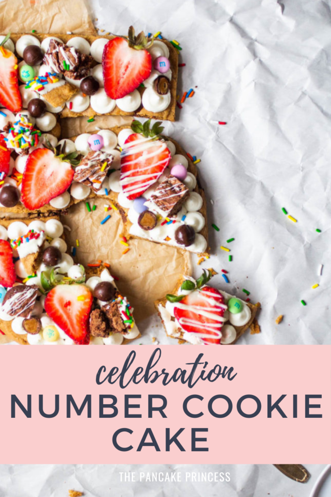 A slice taken out of a birthday cookie cake shaped like the numbers 35 topped with frosting, fruit and candy.