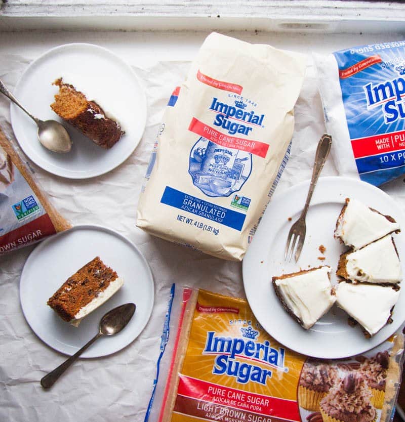Overhead shot of cake slices on white plates with forks surrounded by bags of Imperial Sugar.