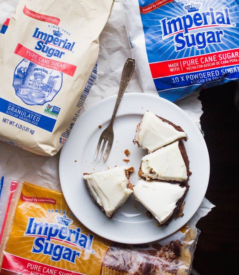 Overhead shot of cake slices on a white plate surrounded by bags of Imperial Sugar.