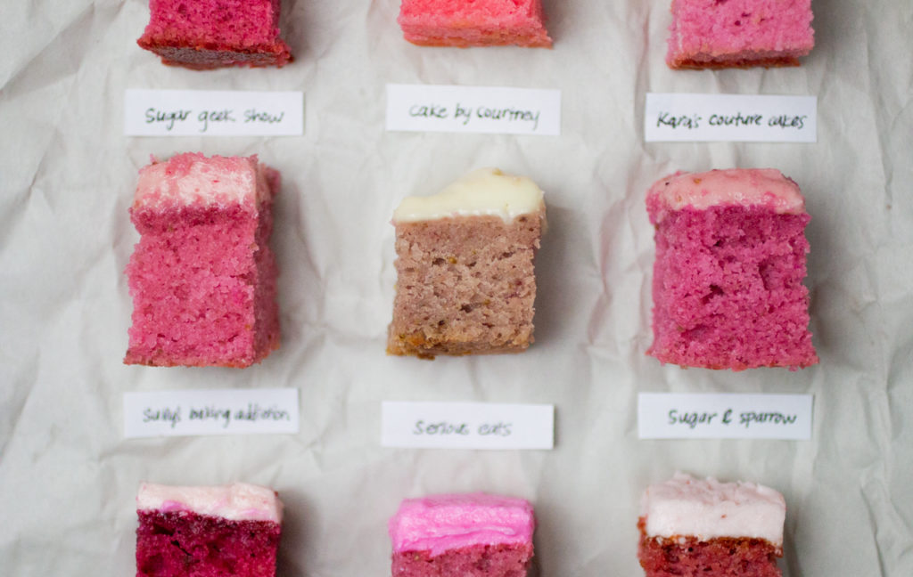several slices of pink iced strawberry cake on white parchment paper.