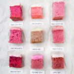 9 squares of different frosted strawberry cake on a crinkled white background.