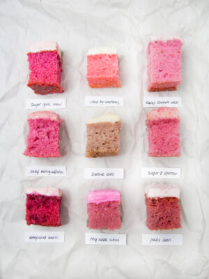 9 squares of different frosted strawberry cake on a crinkled white background.