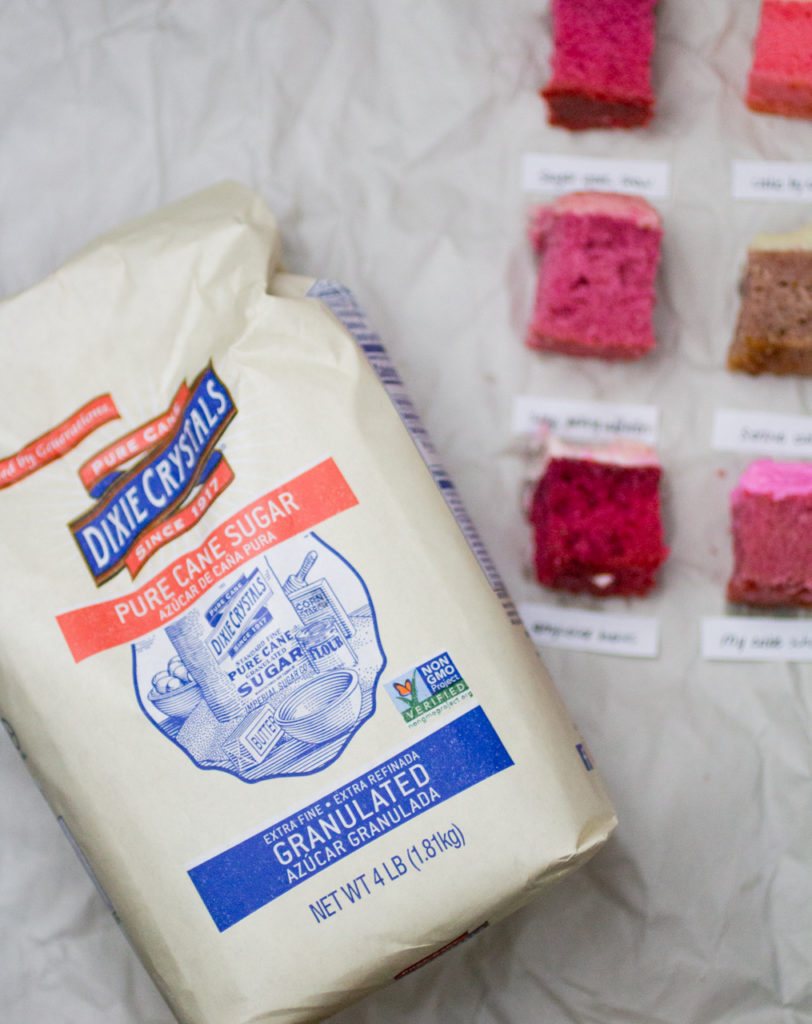 Full bag of Dixie Crystals Imperial Sugar next to 6 slices of strawberry cakes on white parchment paper.