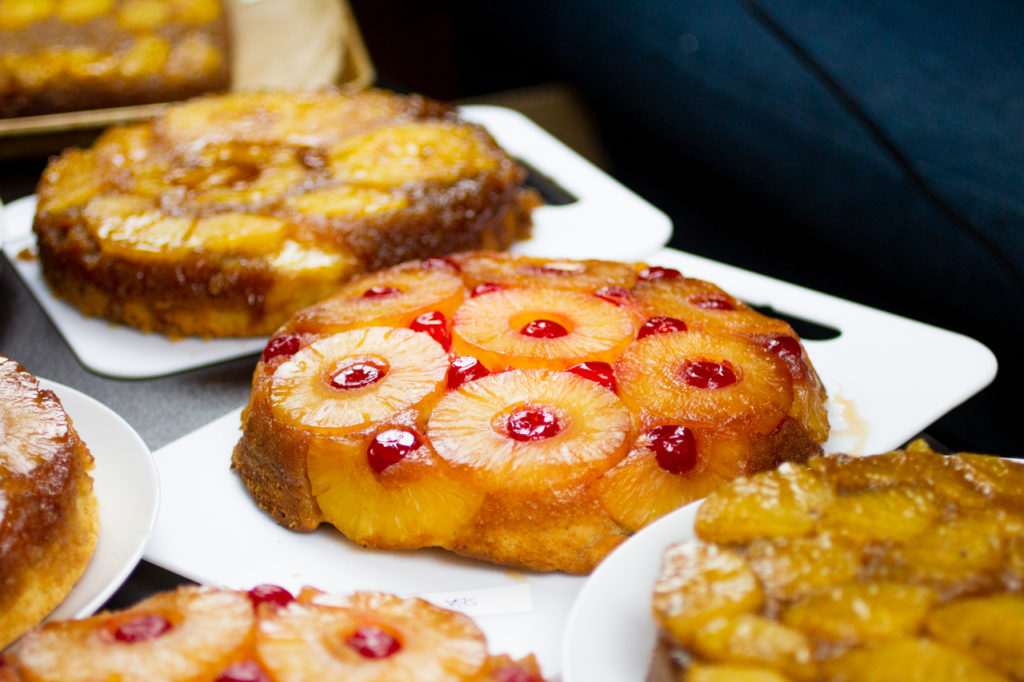 a pineapple upside cake on a white cutting board surrounded by other cakes.
