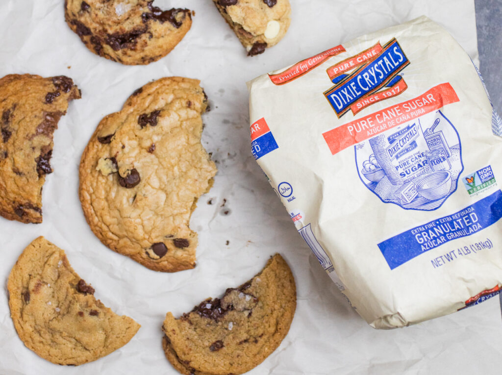 Half eaten chocolate chip cookies next to a bag of Dixie Crystals sugar.