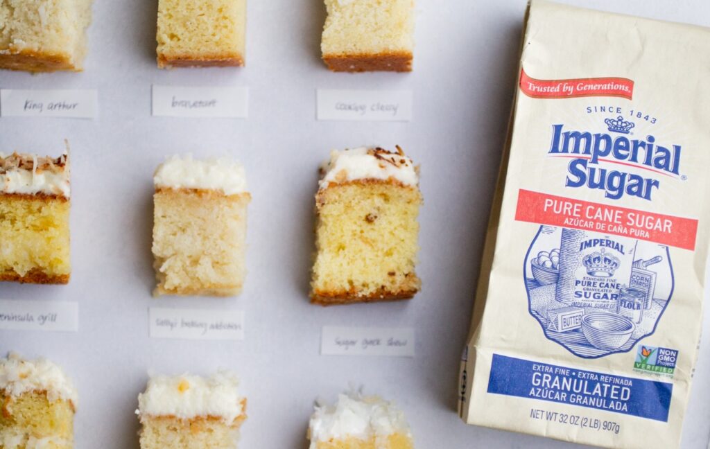 Slices of coconut cake next to a bag of Imperial Sugar.