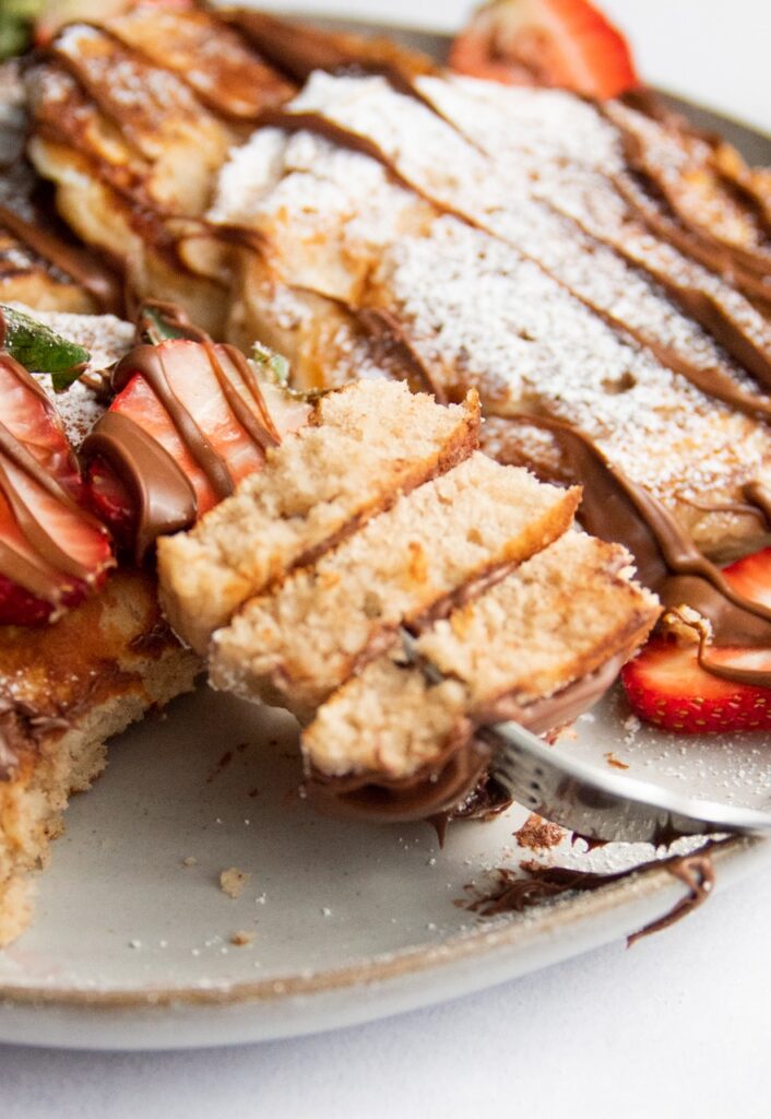 A fork digging into a bite of pancakes.