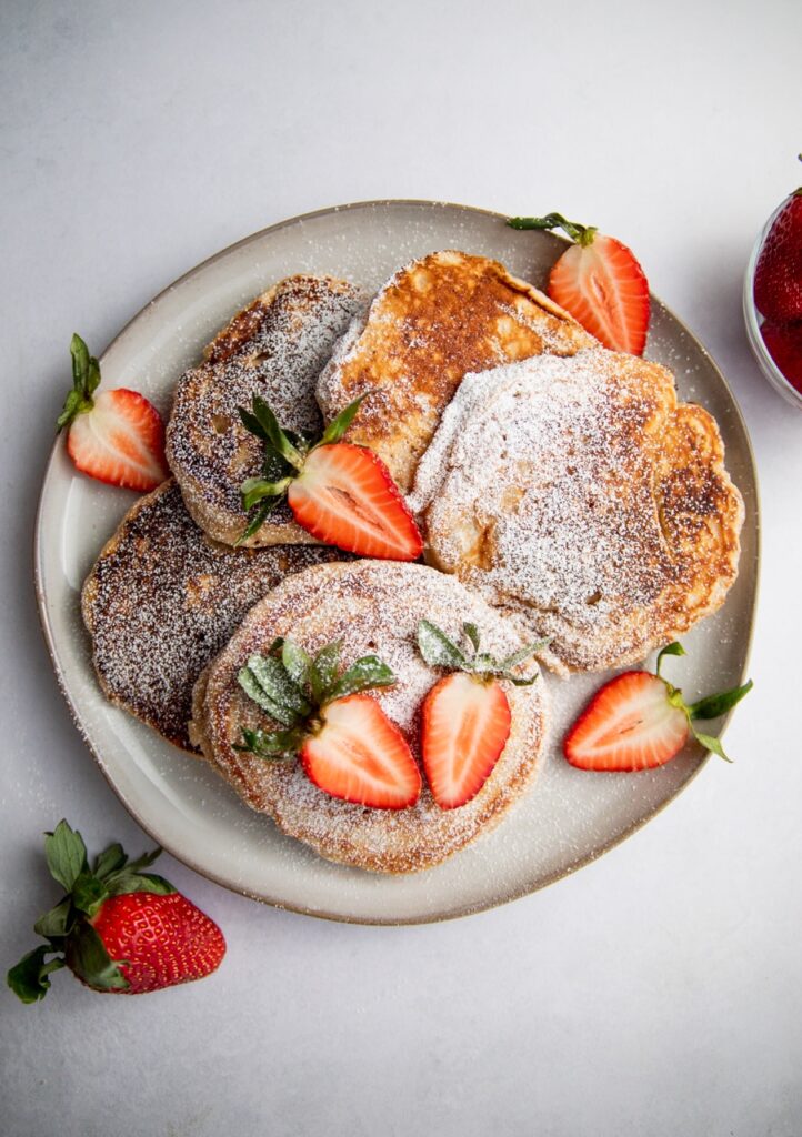 a plate of pancakes drizzled with nutella and strawberries.