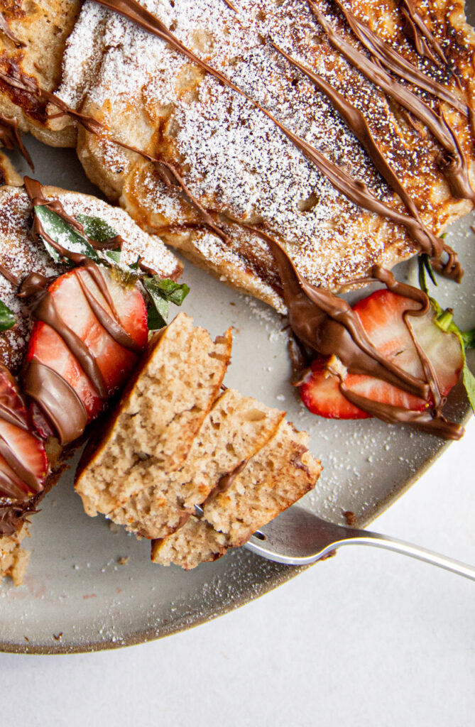 A fork digging into a bite of pancakes.
