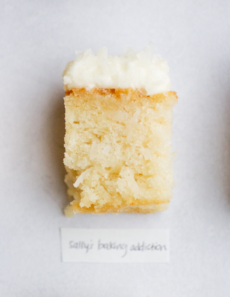 square of frosted coconut cake on a gray background with the label \"sally\'s baking addiction.\"