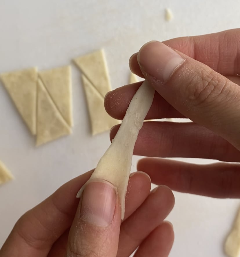 A triangle of puff pastry being stretched out.