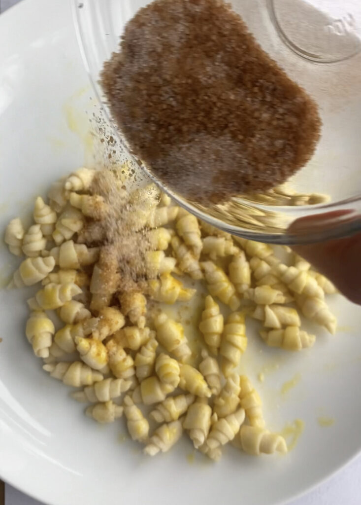 Sprinkling tiny puff pastry croissants with cinnamon sugar.
