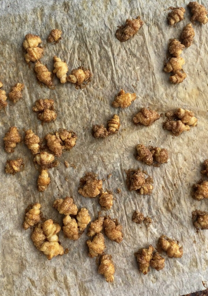 Baked cinnamon sugar mini croissant cereal on parchment paper.