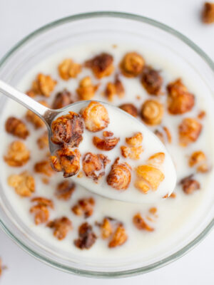 a spoon with tiny croissant cereal in milk.