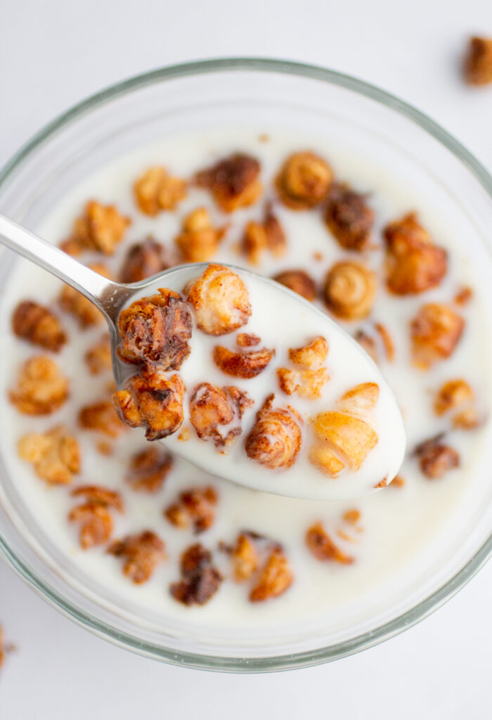 a spoon with tiny croissant cereal in milk.