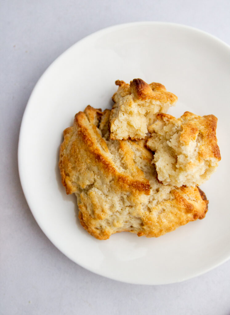 A scone broken into pieces on a white plate.
