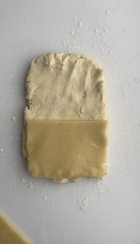 A rectangle of almond paste placed on a rectangle of scone dough.