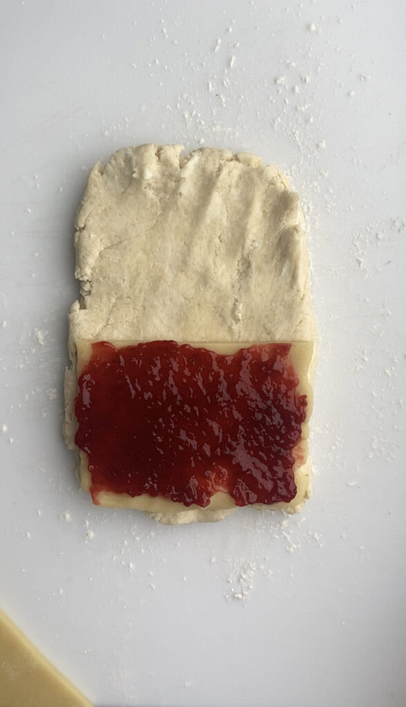 A layer of jam spread over the almond paste on the scone dough.