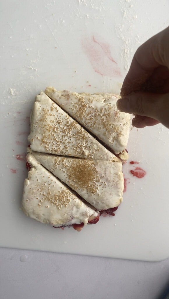 Sprinkling the cut scones with coarse sugar.