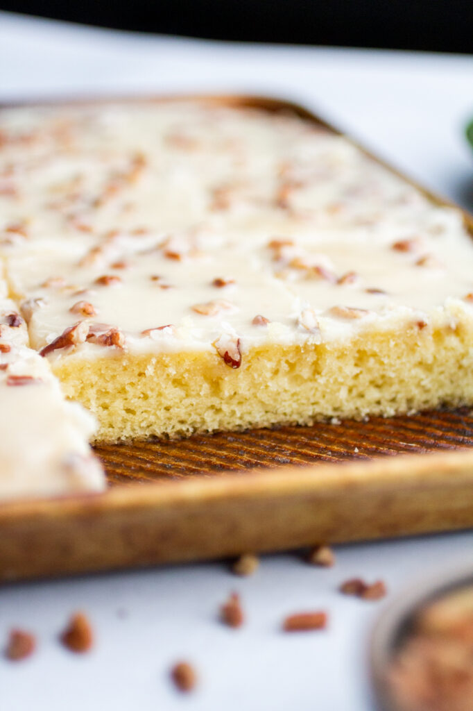 A pan of white Texas sheet cake with a slice removed.